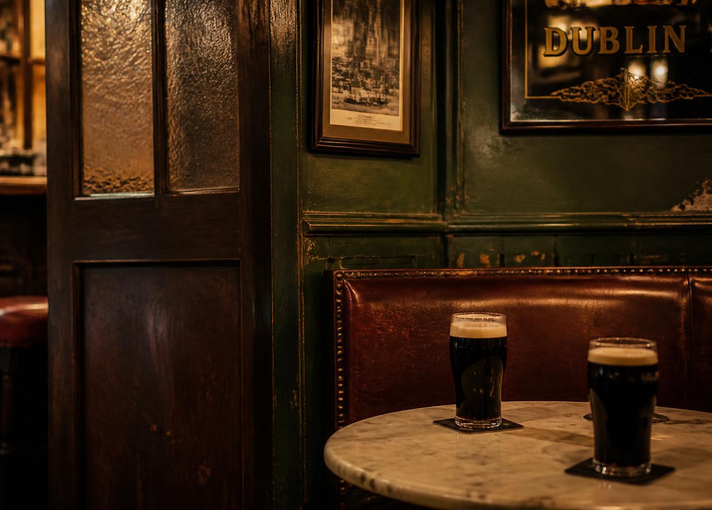 A dark green panelled snug in an old Dublin pub with two pints of stout